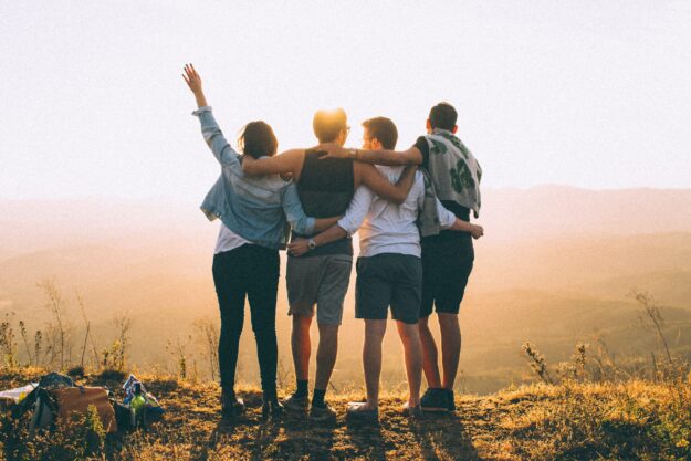 4 people arm in arm facing sunset